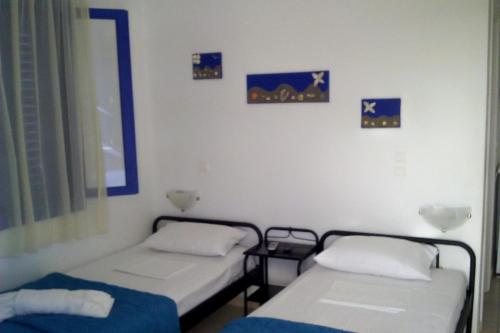 two beds in a room with pictures on the wall at Vigles in Adamas