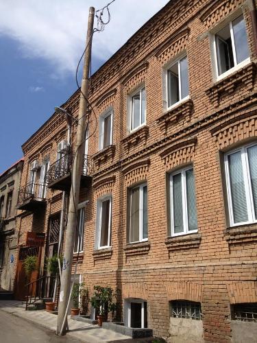a large brick building with windows on a street at Hotel Corner in Tbilisi City