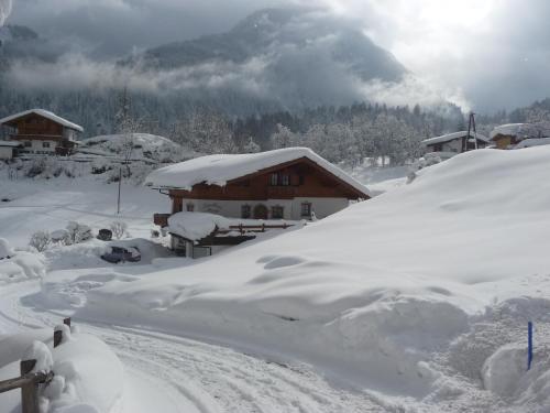 a snow covered house with a mountain in the background at Landhaus Maria in Finkenberg