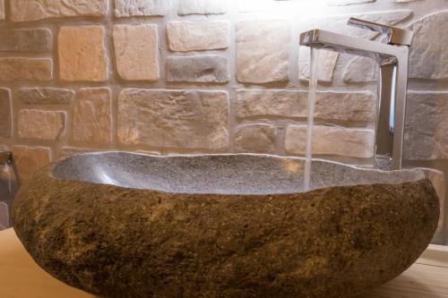 a stone sink with a faucet in a bathroom at Hotel Sogni D'Oro in Camporosso in Valcanale