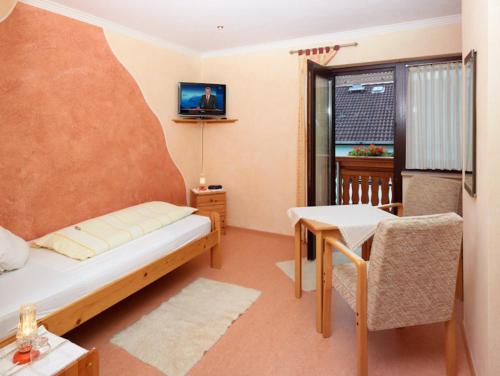 a room with a bed and a table and a television at Hotel Garni Assion in Birgel