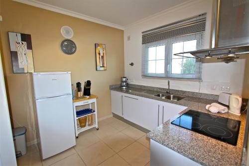 eine Küche mit einem weißen Kühlschrank und einer Spüle in der Unterkunft Villa Amendoeira 4 - Clever Details in Vilamoura
