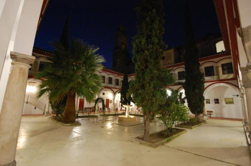 a courtyard of a building with palm trees at night at Hotel Hospederia San Francisco in Priego de Córdoba