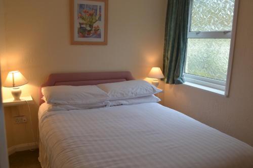 a bedroom with a bed with two lamps and a window at Ashbury Tor in Torquay