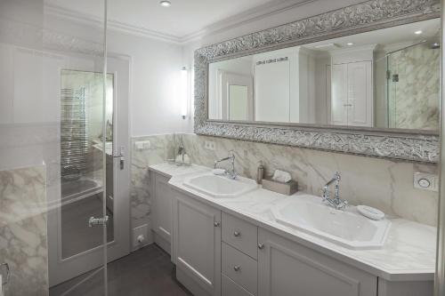 a white bathroom with two sinks and a shower at Ferienhaus Weetstich in Archsum