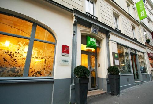 a store front with two potted plants on a street at ibis Styles Paris Cadet Lafayette in Paris
