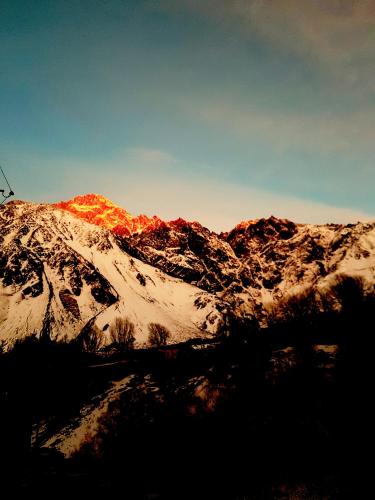 a mountain covered in snow with the sun shining on it at Cozy Hotel Kazbegi in Stepantsminda