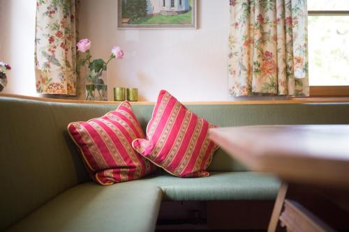 ジルバータールにあるHotel-Pension Fanesklaのベンチに座ったピンクと赤の枕2つ