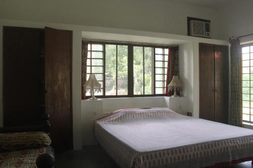 a bedroom with a bed and two windows at Isai Ambalam guest house in Puducherry