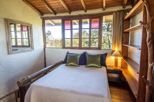 a bedroom with a bed in a room with windows at Pousada Morro das Palmeiras in Praia do Rosa