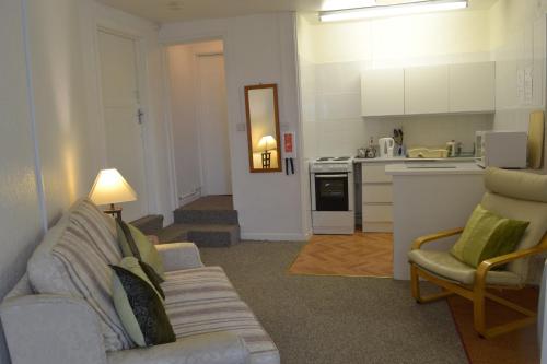 een woonkamer met een bank en een keuken bij Huccaby Tor Apartmernt in Torquay