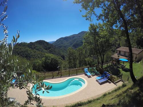 a swimming pool with chairs and mountains in the background at Agriturismo Le Scope in Molazzana