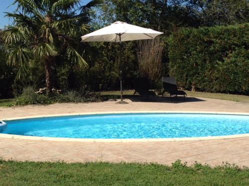 a pool with an umbrella and a chair and a table with an umbrella at Les Glycines in Saint-Gaudens