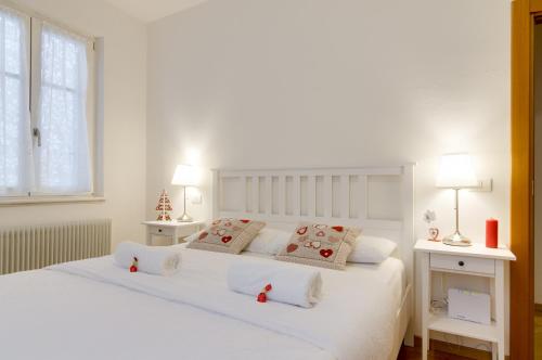 a white bedroom with a white bed with two lamps at B&B and Apartments Al Duomo in Trento