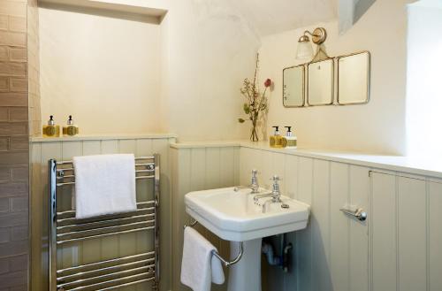 ein Bad mit einem Waschbecken und einem Spiegel in der Unterkunft The Bull Hotel in Fairford