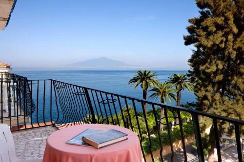 a book on a table on a balcony with the ocean at Hotel Continental in Sorrento