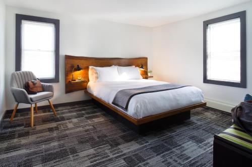 ein Schlafzimmer mit einem Bett und einem Stuhl und Fenstern in der Unterkunft Main and Mountain in Ludlow