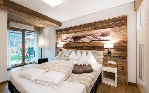 a bedroom with a large bed with a wooden wall at Apartments Chalet Anna in Ortisei