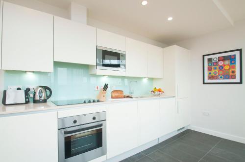 a white kitchen with white cabinets and appliances at Cleyro Serviced Apartments - Finzels Reach in Bristol