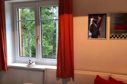 a window with red curtains and a cat toy on a window sill at Ferienhaus im Wald in Edelschrott