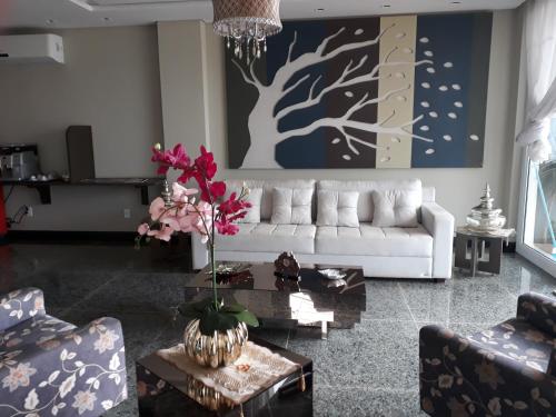 a living room with a white couch and a tree painting at Pak Suítes Hotel in Luis Eduardo Magalhaes