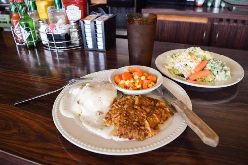 a table with two plates of food and a bowl of vegetables at Oregon Trail Motel and Restaurant in Baker City