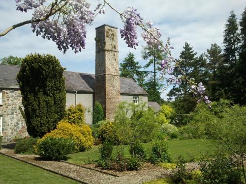 an old house with a chimney and a garden at Newforge House in Moira