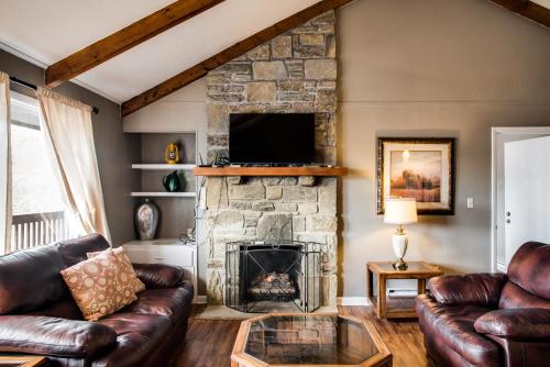 a living room with a stone fireplace and leather couches at Cliff Dwellers Inn in Blowing Rock
