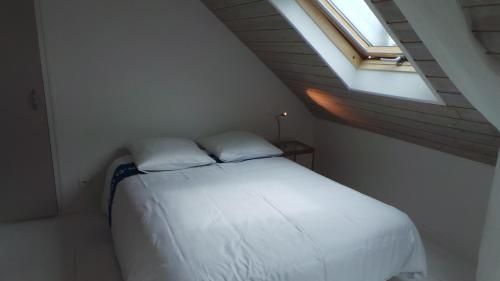 un lit blanc dans une chambre avec une fenêtre dans l'établissement Lesneven Appart Nuitee, à Lesneven