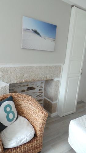 une chambre avec une chaise en osier à côté d'une cheminée dans l'établissement Lesneven Appart Nuitee, à Lesneven