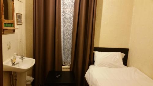 Baño pequeño con cama y lavabo en Best Inn Hotel, en Ilford