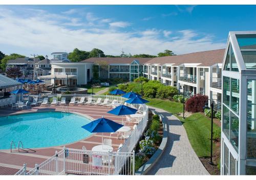 a resort pool with umbrellas and chairs and buildings at Hyannis Harbor Hotel in Hyannis