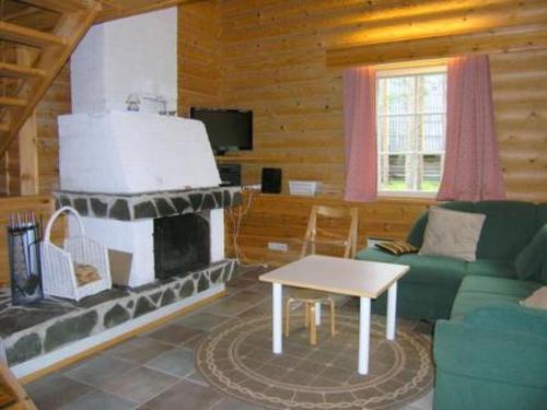 ein Wohnzimmer mit einem Kamin in einer Blockhütte in der Unterkunft Holiday Home Kangastus a by Interhome in Suomutunturi