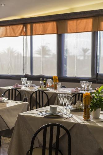 a dining room with tables and chairs and windows at Hotel Bixio in Lido di Camaiore