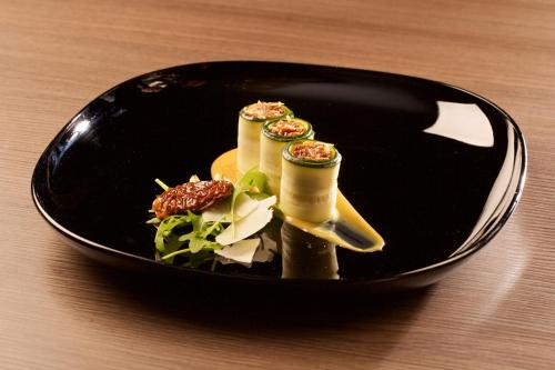 a black plate with food on a wooden table at Hotel Marta in Oława