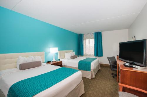 a hotel room with two beds and a flat screen tv at Howard Johnson by Wyndham Evansville East in Evansville