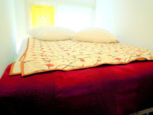 a bed with a red blanket and two pillows at MissOrtelia B&B in Amsterdam