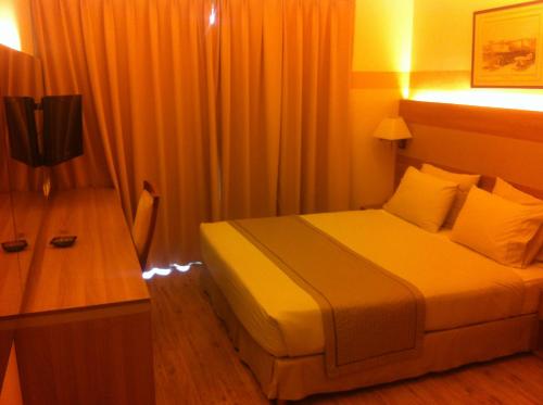 a bedroom with a bed and a desk with a television at Padova Hotel in Beirut