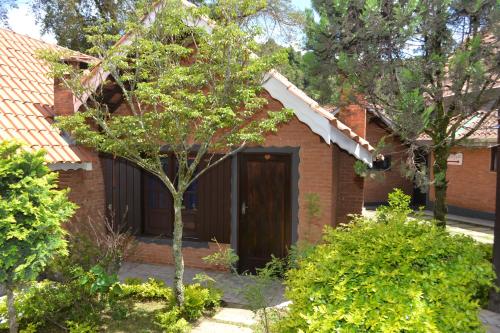 a brick house with a brown door in a yard at Pousada Sol Nascente in Monte Verde