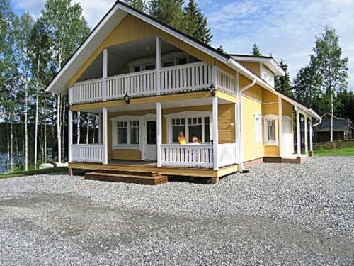 a large yellow house with a large porch at Holiday Home Mielikki by Interhome in Kurkimaki