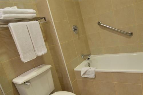 a bathroom with a tub and a toilet and towels at Hotel Diego de Almagro Puerto Montt in Puerto Montt