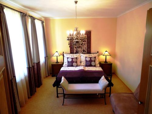 a bedroom with a bed and a chair and a chandelier at Buda Panzió in Győr