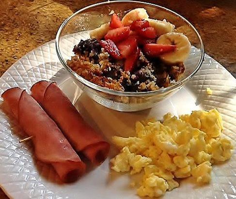 a plate of breakfast food with a bowl of fruit at Caldwell House Bed and Breakfast in Salisbury Mills