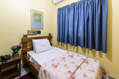 um quarto com uma cama e uma cortina azul em Hotel Paraiso em São Paulo