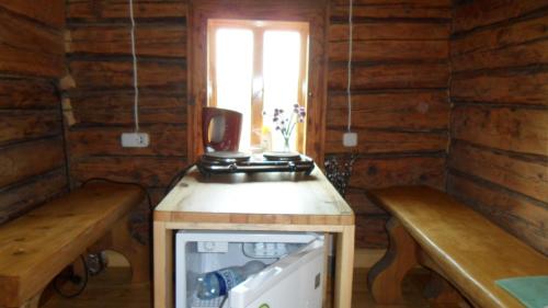 una pequeña cocina con 2 bancos en una cabaña de madera en Guest house Oaze, en Miglāni