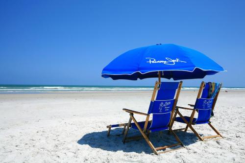 duas cadeiras e um guarda-sol numa praia em Guy Harvey Resort on Saint Augustine Beach em Saint Augustine Beach