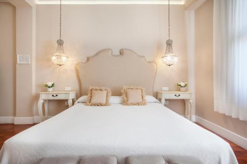 a white bed sitting under a lamp next to a white wall at Hi Valencia Boutique in Valencia