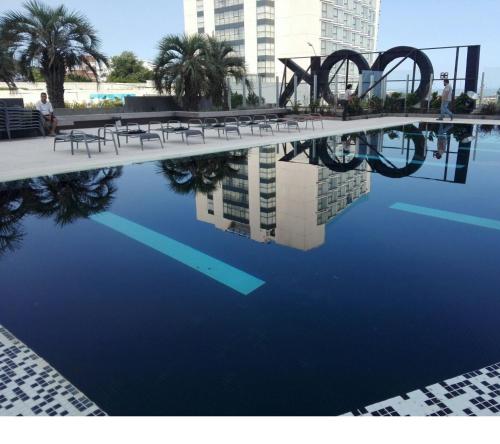 una piscina con bancos y un reflejo en el agua en LOOK BRAVA 802, en Punta del Este