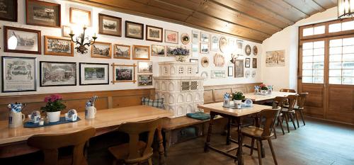 un restaurant avec des tables, des chaises et des photos sur le mur dans l'établissement Werdenfelser Hof, à Garmisch-Partenkirchen