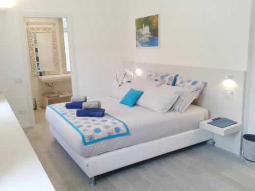 a white bedroom with a white bed with blue pillows at Hotel Madal&ugrave; in Rimini